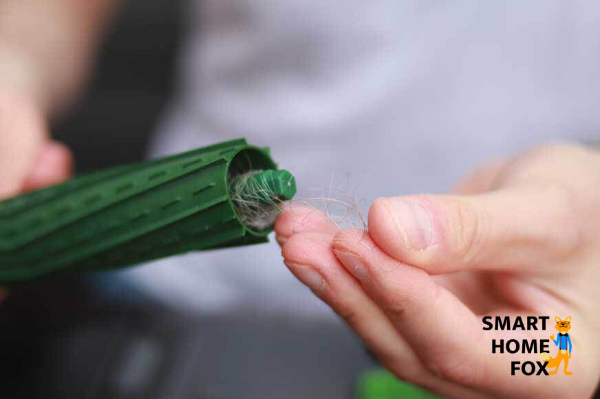 Festsitzende Haare werden aus den beiden Gummibürsten des iRobot Roomba j7 entfernt